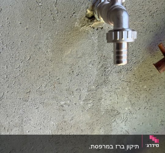 ברז מים חיצוני עם חיבור לצינור מותקן על קיר בטון